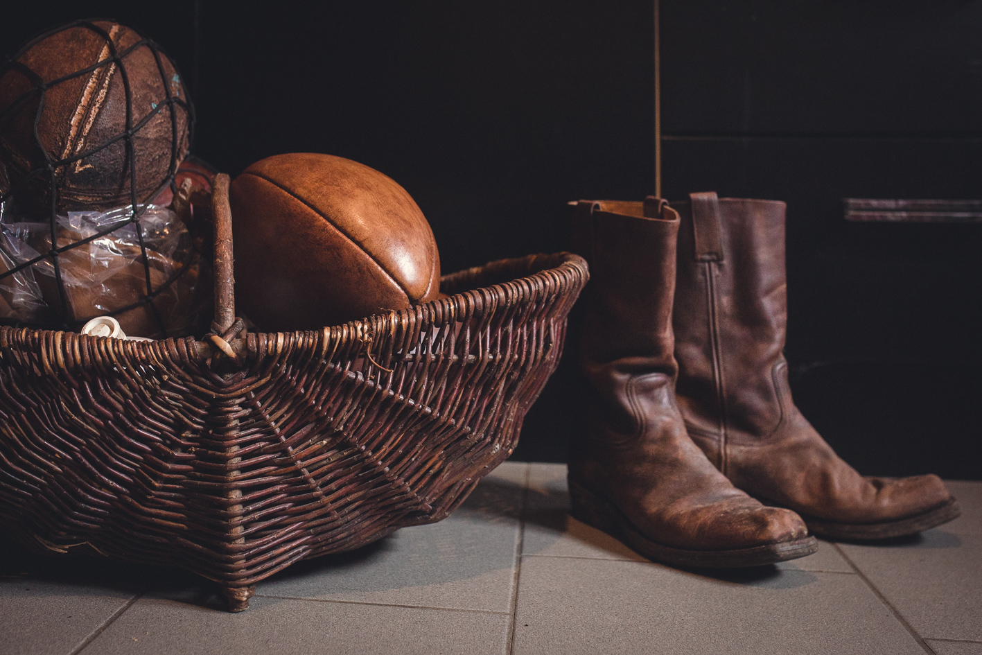 une pairs de botte au style cowboy sont posées a cote d'un panier avec un ballon de rugby